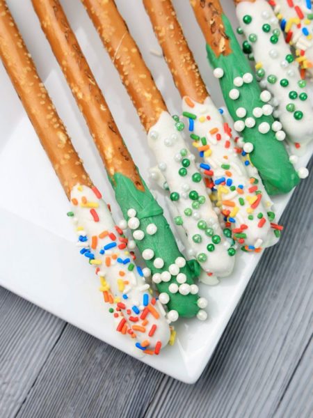 The St. Patrick's Pretzel Rods comes on a white plate on a white striped napkin with a gray wood backdrop.