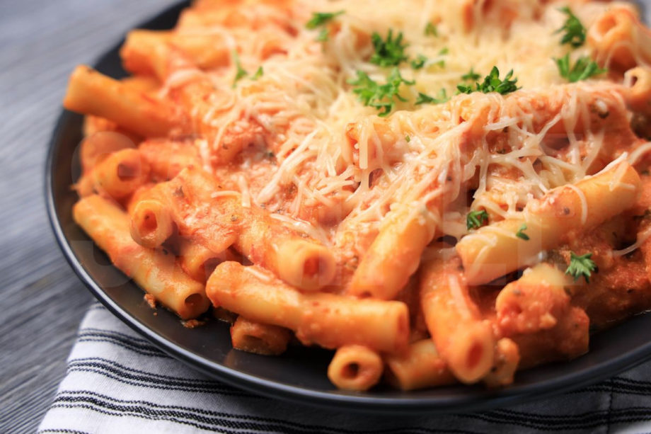 The Five Cheese Ziti Al Forno Olive Garden Copycat comes on a gray plate with a white striped napkin on a gray wood backdrop.