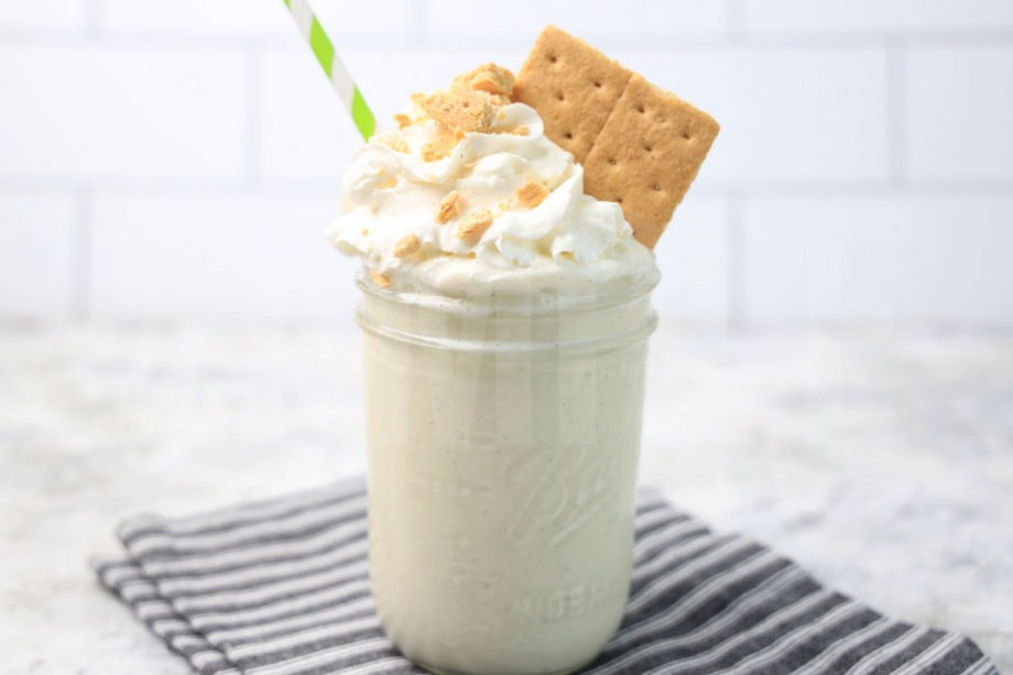 The Key Lime Pie Milkshake comes in a glass jar on a gray striped napkin on a marble backdrop.