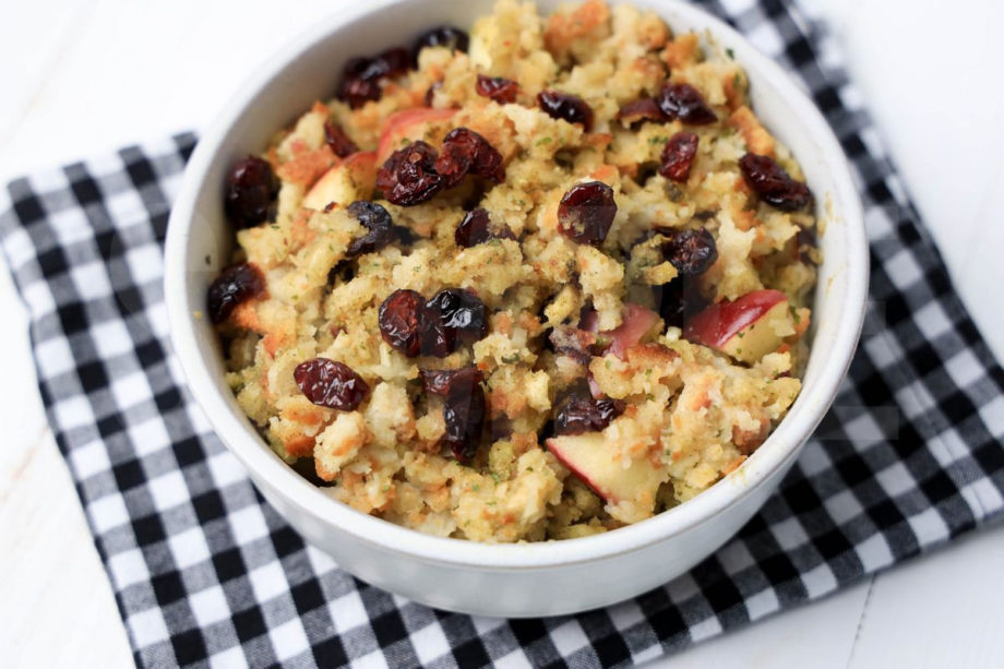 The Cranapple Stuffing comes in a white bowl with a plaid napkin on a white wood backdrop.