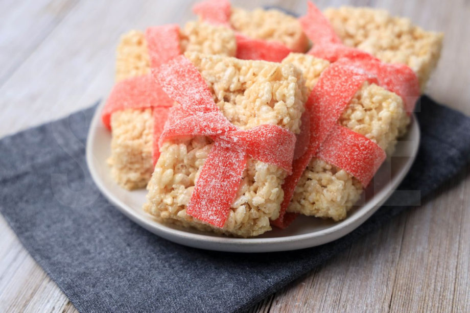 The Present Rice Krispies Treats comes on a white plate with a denim napkin on a rustic wood backdrop.