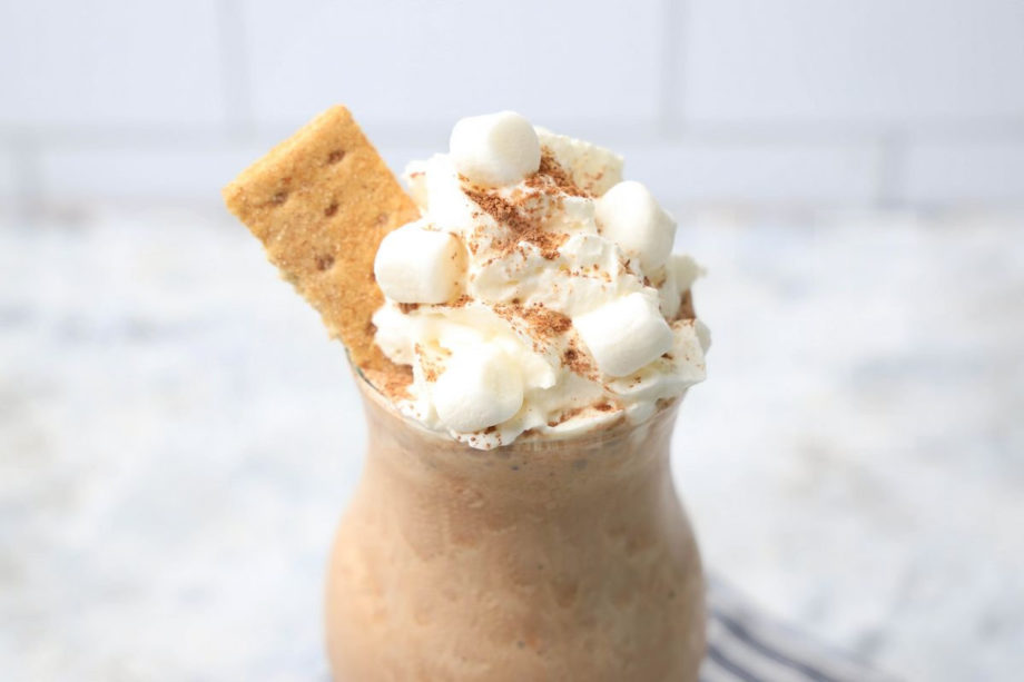 The S'mores Milkshake comes in a glass with a gray striped napkin on a marble wood backdrop.