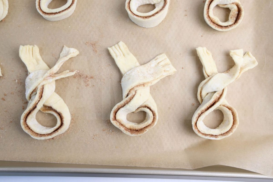 The Cinnamon Sugar Bunny Twists comes on a olive wood cutting board with gray and white cloth on white wood backdrop.