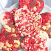 The Heart Raspberry Nut Chocolates comes on a white plate with a light gray and white striped cloth on a gray wood backdrop.