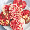 The Heart Raspberry Nut Chocolates comes on a white plate with a light gray and white striped cloth on a gray wood backdrop.