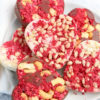 The Heart Raspberry Nut Chocolates comes on a white plate with a white and red heart cloth on a gray wood backdrop.