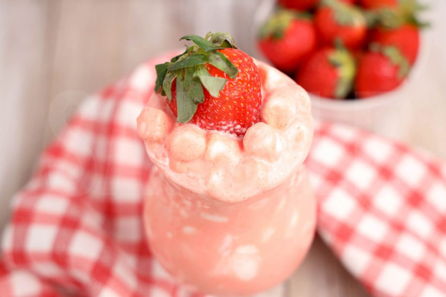 The Strawberry Fluff comes in a clear glass with a red and white plaid cloth on a rustic wood backdrop.