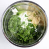 The Tzatziki Dip comes in a white bowl on a wood cutting board with a olive green cloth on a white wood backdrop.
