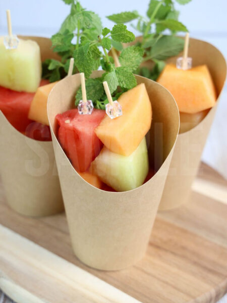 The Melon Fruit Cups comes in a brown fry cup with rustic wood backdrop.