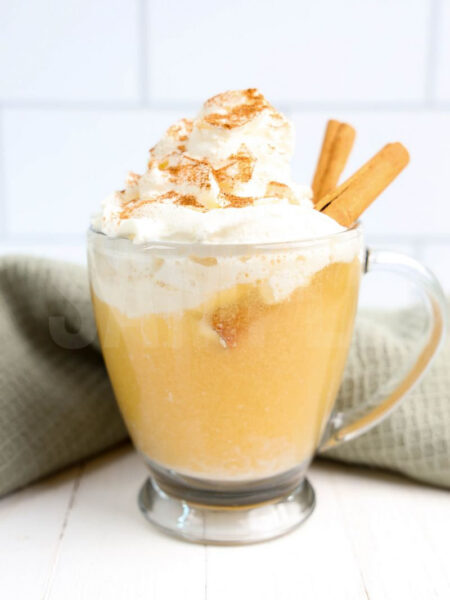 The Apple Cider Float comes in a glass with handle on a with white wood backdrop.