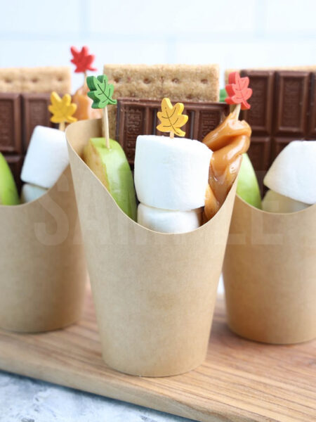 The Caramel Apple S’mores Cups comes in a brown fry cup with marble wood backdrop.