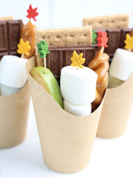 The Caramel Apple S’mores Cups comes in a brown fry cup with white wood backdrop.