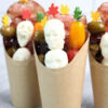 The Horror Movie Charcuterie Cups comes in a brown fry cup with gray wood backdrop.