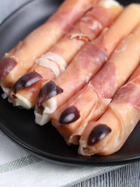 The Prosciutto Witch Fingers come on a gray plate with black wood backdrop.