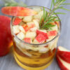 The Apple Cider Whiskey comes in a glass on a gray wood backdrop.