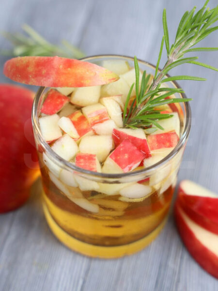 The Apple Cider Whiskey comes in a glass on a gray wood backdrop.